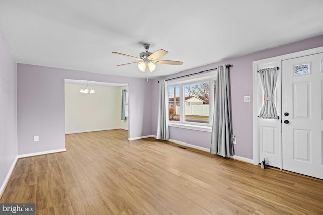 entryway with ceiling fan with notable chandelier and light wood-type flooring