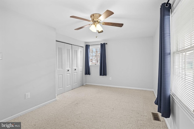 unfurnished bedroom featuring a closet, ceiling fan, and light colored carpet