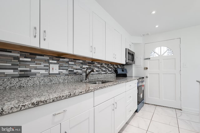 kitchen with white cabinetry, sink, stainless steel appliances, and light stone counters