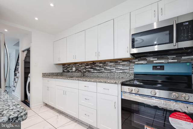 kitchen featuring appliances with stainless steel finishes, tasteful backsplash, sink, white cabinets, and washer / dryer