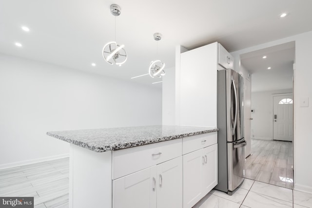 kitchen with stainless steel fridge, light stone counters, light hardwood / wood-style flooring, white cabinetry, and hanging light fixtures