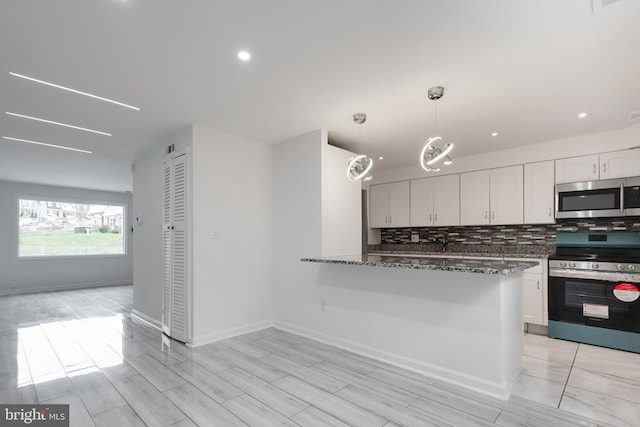 kitchen with pendant lighting, dark stone counters, white cabinets, appliances with stainless steel finishes, and tasteful backsplash