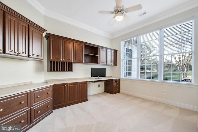 unfurnished office featuring crown molding, light colored carpet, and built in desk