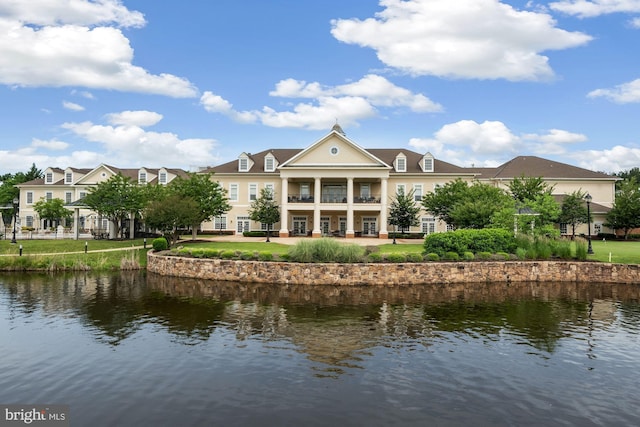 back of house featuring a lawn, a balcony, and a water view