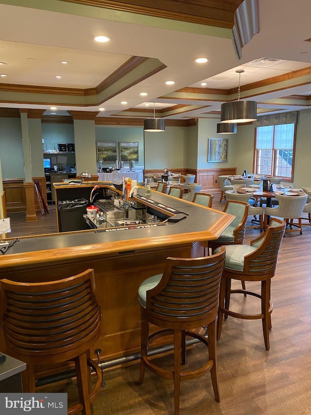 bar featuring a tray ceiling, ornamental molding, pendant lighting, and wood-type flooring