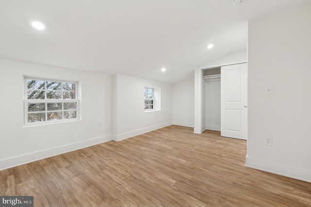 unfurnished bedroom featuring a closet, lofted ceiling, and light wood-type flooring