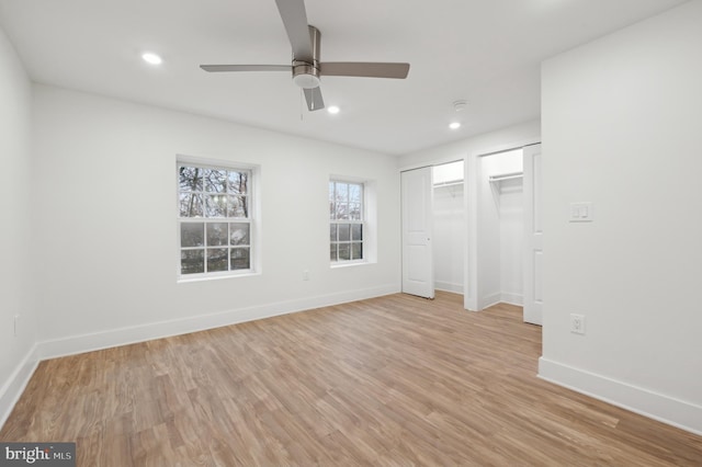 unfurnished bedroom with multiple closets, ceiling fan, and light hardwood / wood-style floors