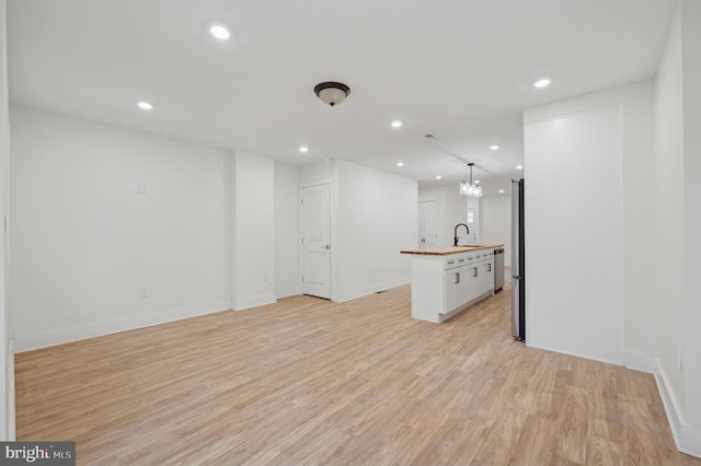 unfurnished living room with light hardwood / wood-style flooring, a notable chandelier, and sink