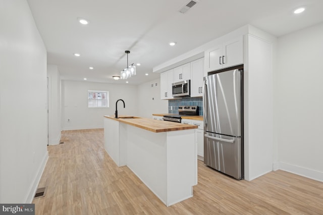 kitchen featuring white cabinetry, sink, hanging light fixtures, stainless steel appliances, and wood counters