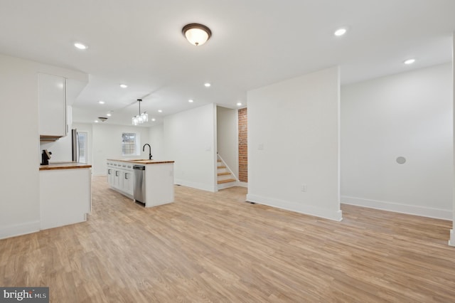 kitchen featuring white cabinetry, light hardwood / wood-style flooring, stainless steel dishwasher, butcher block countertops, and pendant lighting