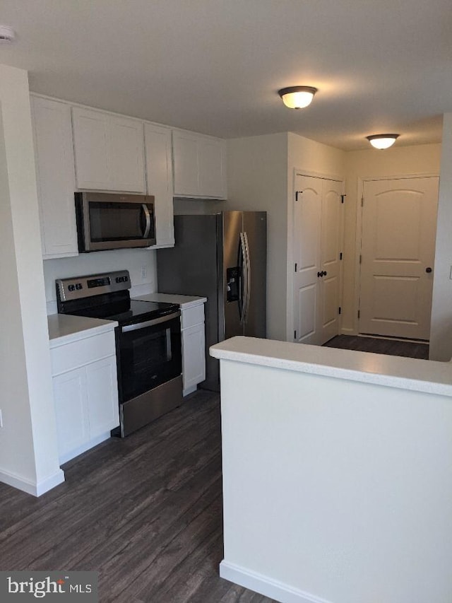 kitchen with appliances with stainless steel finishes, dark hardwood / wood-style flooring, and white cabinetry