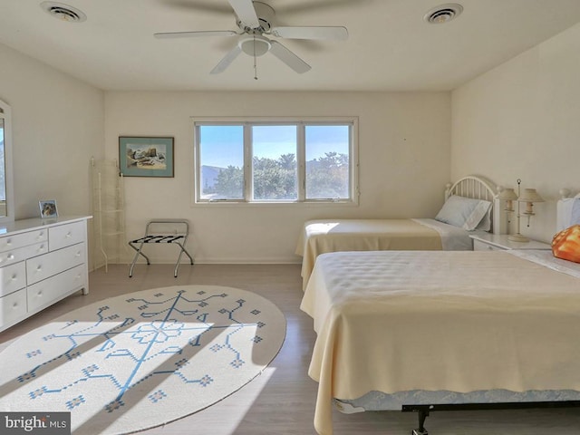 bedroom with a ceiling fan, visible vents, and wood finished floors