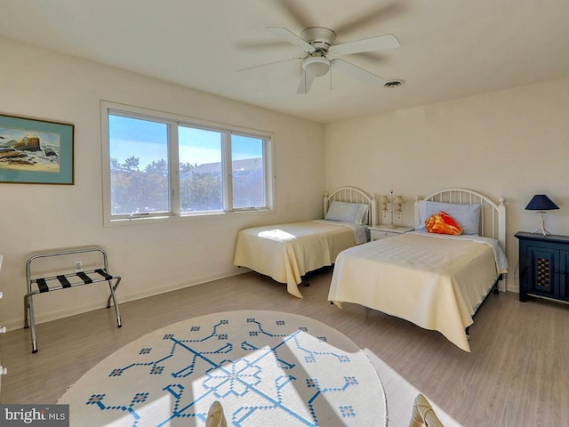 bedroom with light wood finished floors, baseboards, visible vents, and ceiling fan