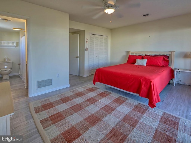 bedroom featuring baseboards, visible vents, ensuite bathroom, and wood finished floors