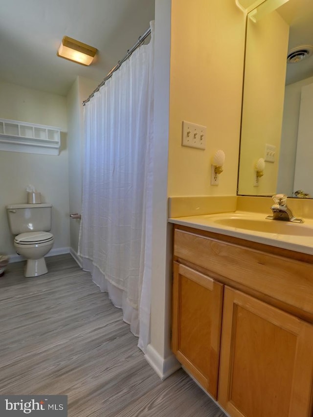 full bathroom with toilet, wood finished floors, visible vents, vanity, and baseboards