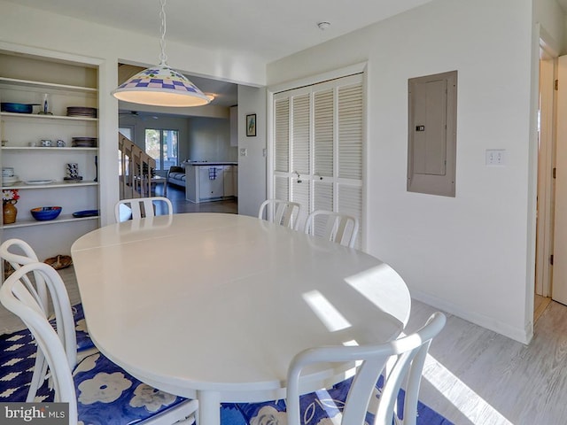 dining area with stairway, wood finished floors, electric panel, and baseboards