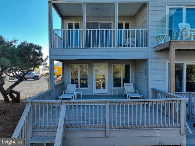 rear view of house featuring a wooden deck and a balcony