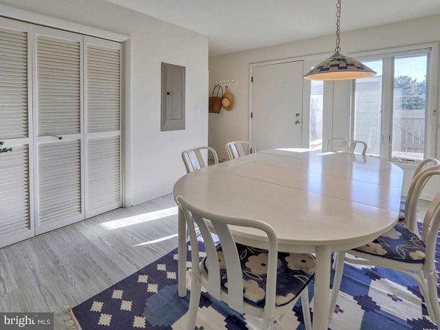 dining area featuring electric panel, light wood-style flooring, and baseboards