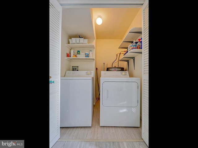 clothes washing area with light wood-type flooring, laundry area, and independent washer and dryer