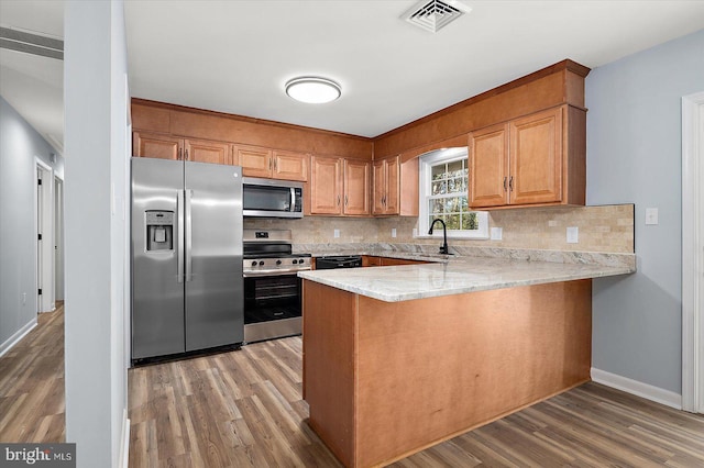 kitchen with backsplash, sink, wood-type flooring, and stainless steel appliances