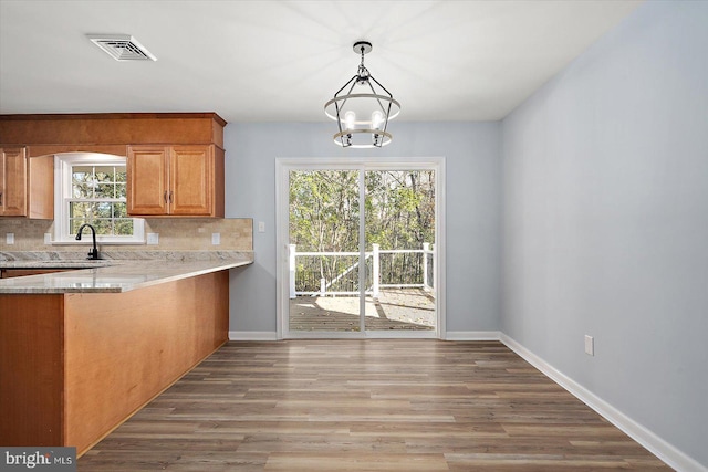 kitchen featuring backsplash, hardwood / wood-style flooring, an inviting chandelier, and hanging light fixtures