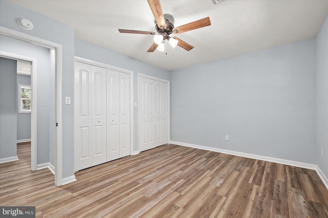 unfurnished bedroom featuring multiple closets, ceiling fan, and light hardwood / wood-style floors