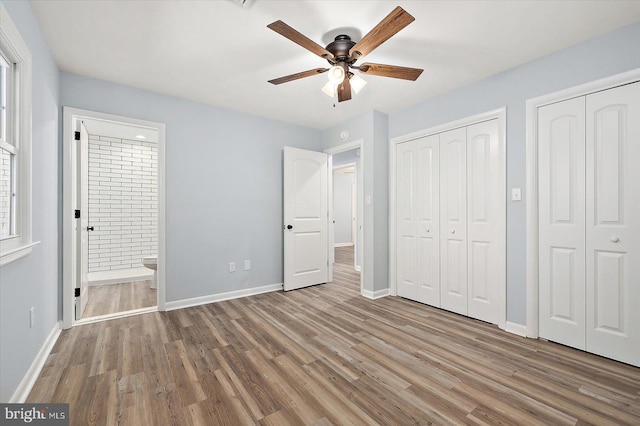 unfurnished bedroom with connected bathroom, ceiling fan, two closets, and light wood-type flooring