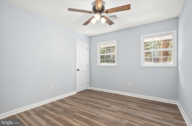 empty room with ceiling fan, a healthy amount of sunlight, and dark hardwood / wood-style flooring