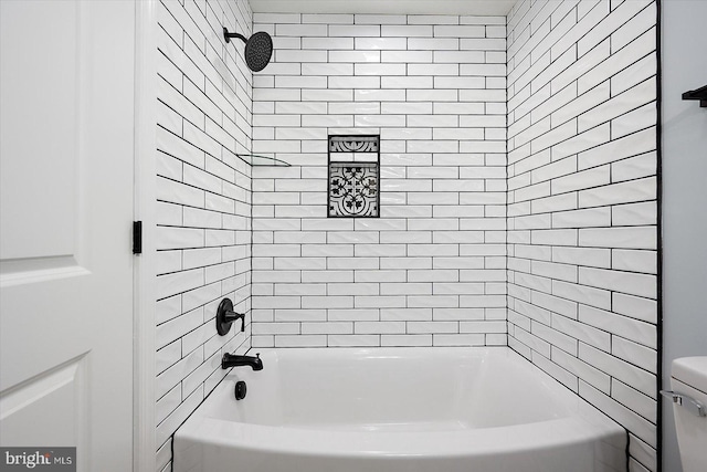 bathroom featuring toilet and tiled shower / bath