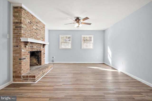 unfurnished living room with ceiling fan, a fireplace, and light wood-type flooring