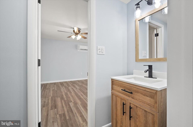 bathroom with a wall mounted air conditioner, hardwood / wood-style floors, vanity, and ceiling fan