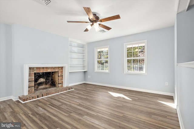 unfurnished living room featuring ceiling fan, wood-type flooring, built in features, and a brick fireplace