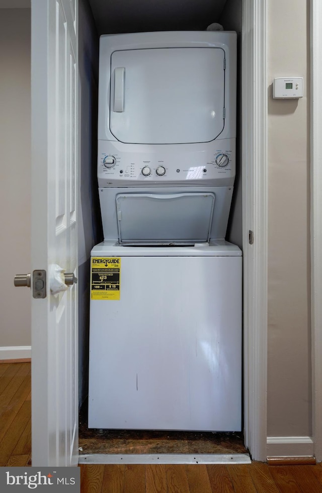 laundry area with dark hardwood / wood-style floors and stacked washer / dryer