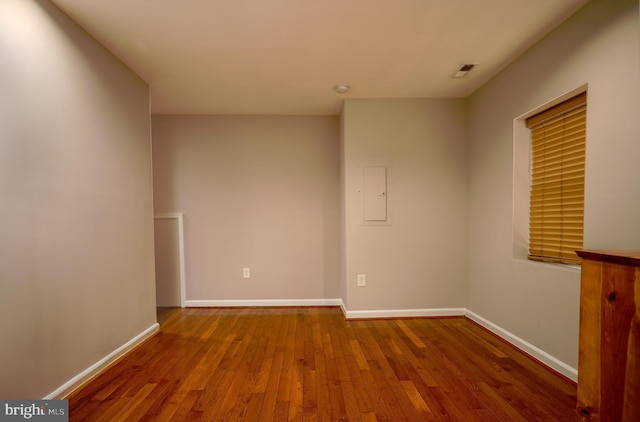 empty room featuring electric panel and hardwood / wood-style floors