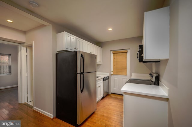 kitchen with light hardwood / wood-style flooring, white cabinets, and appliances with stainless steel finishes