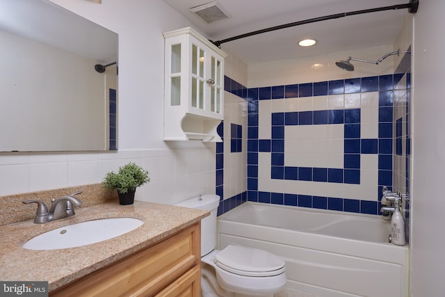 full bathroom featuring vanity, tile walls, toilet, and tiled shower / bath