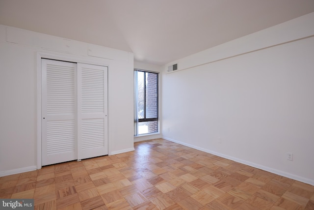 unfurnished bedroom featuring light parquet floors and a closet