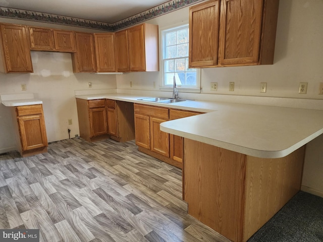 kitchen featuring kitchen peninsula, light wood-type flooring, and sink