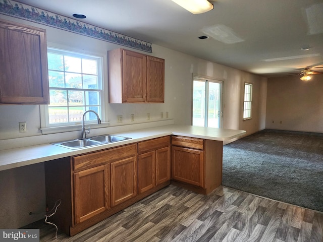 kitchen featuring kitchen peninsula, ceiling fan, dark wood-type flooring, and sink