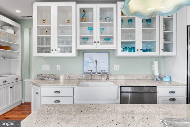 kitchen with light stone countertops, dark hardwood / wood-style floors, sink, white cabinetry, and stainless steel dishwasher