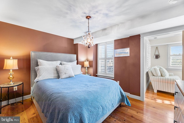 bedroom with an inviting chandelier, multiple windows, and light wood-type flooring