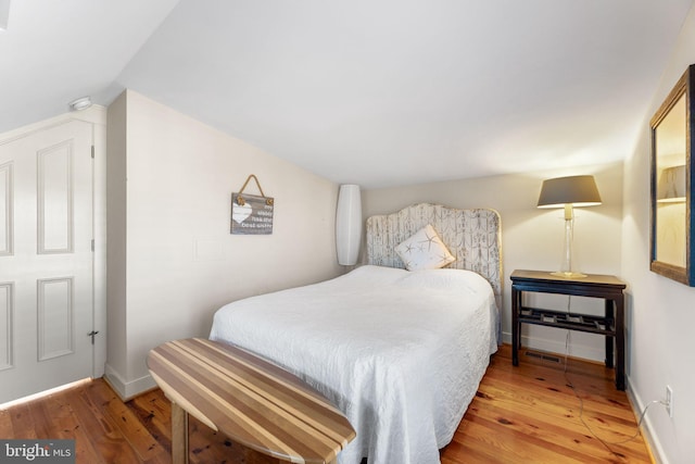 bedroom featuring vaulted ceiling and wood-type flooring