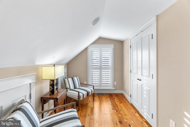 sitting room with light wood-type flooring and vaulted ceiling