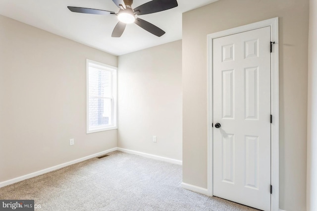 carpeted spare room featuring ceiling fan