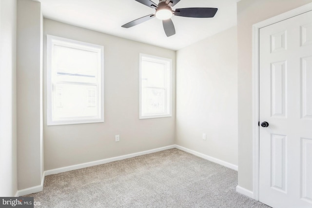 empty room with ceiling fan, light colored carpet, and a wealth of natural light