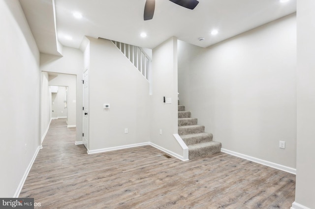 stairs featuring ceiling fan and wood-type flooring