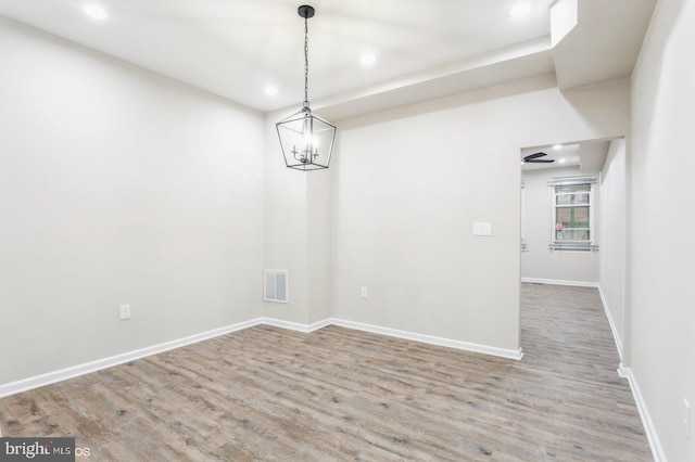 unfurnished dining area featuring hardwood / wood-style flooring and ceiling fan with notable chandelier