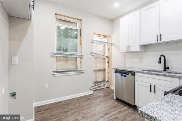 kitchen with light stone counters, white cabinetry, stainless steel dishwasher, and sink