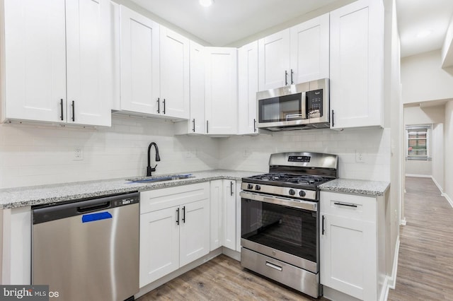 kitchen with white cabinets, light wood-type flooring, stainless steel appliances, and sink