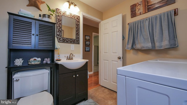 bathroom featuring hardwood / wood-style floors, vanity, toilet, and separate washer and dryer